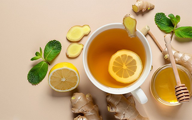 Tasse Tee mit Zitronen, Ingwer und einer kleinen Schale Honig